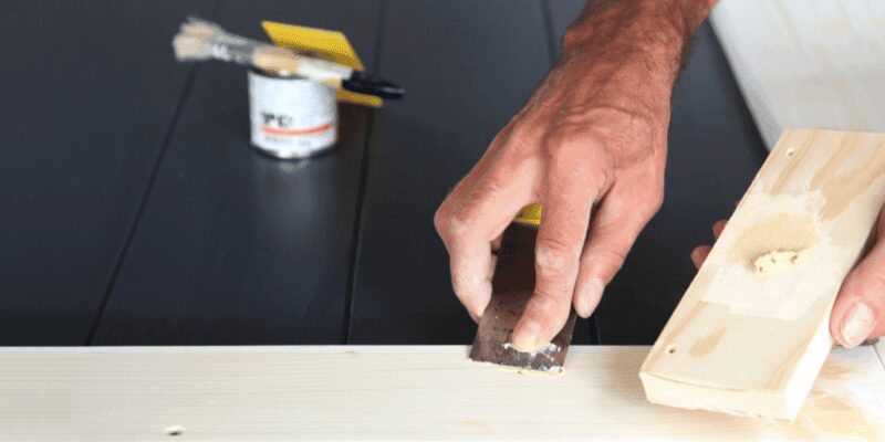 applying wood filler to fill a crack in a wood surface before staining