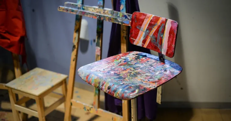 Wooden chair covered in dried, splattered acrylic paint after use as an art studio seat
