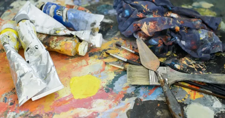 Acrylic paint tubes, brushes, and palette knife used for mixing skin tone colors