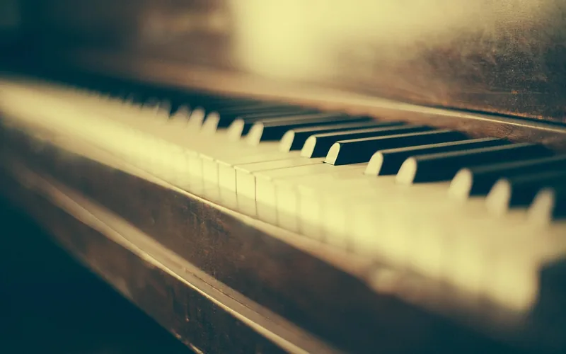 Vintage upright piano keyboard and wooden case in warm light