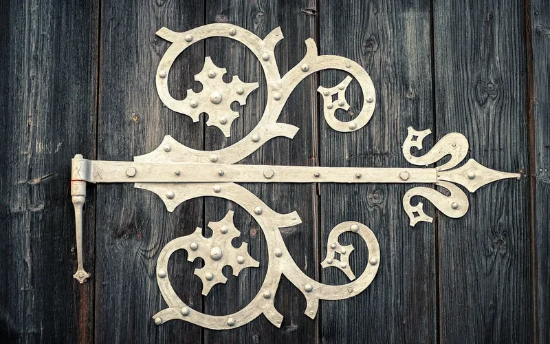 Large decorative strap hinge on weathered vertical plank door boards