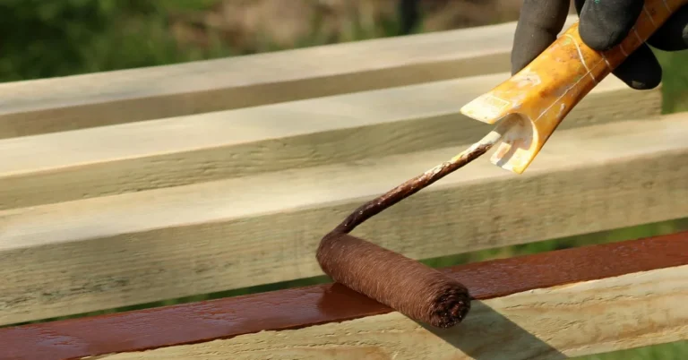 Roller applying primer to a wood board before painting birch plywood