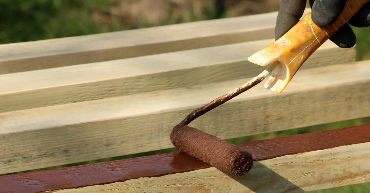 Roller applying primer to a wood board before painting birch plywood