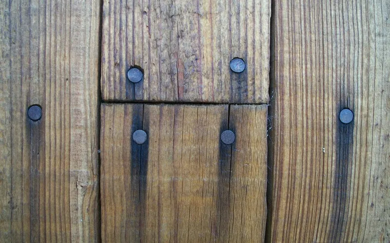 Dark iron-tannin stain streaks running down from nail heads on wood boards