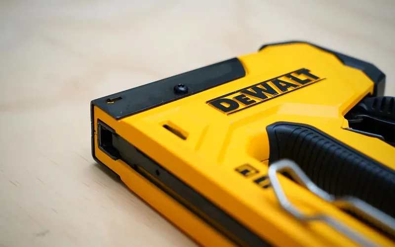 pneumatic brad nailer positioned on a wood board for blind nailing