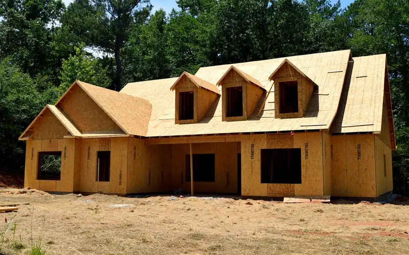 carpenter framing a new house with plywood sheathing and roof trusses carpenter framing a new house with plywood sheathing and roof trusses