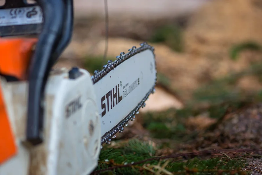 Close-up of a chainsaw guide bar and chain, showing the groove that bar oil has to keep coated