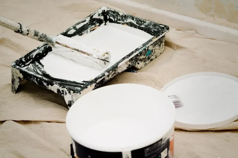 Paint roller tray and bucket on a drop cloth during a stripping and refinishing project