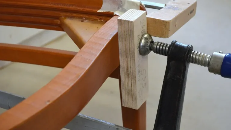 Bar clamp holding a glued wooden chair frame joint while it dries