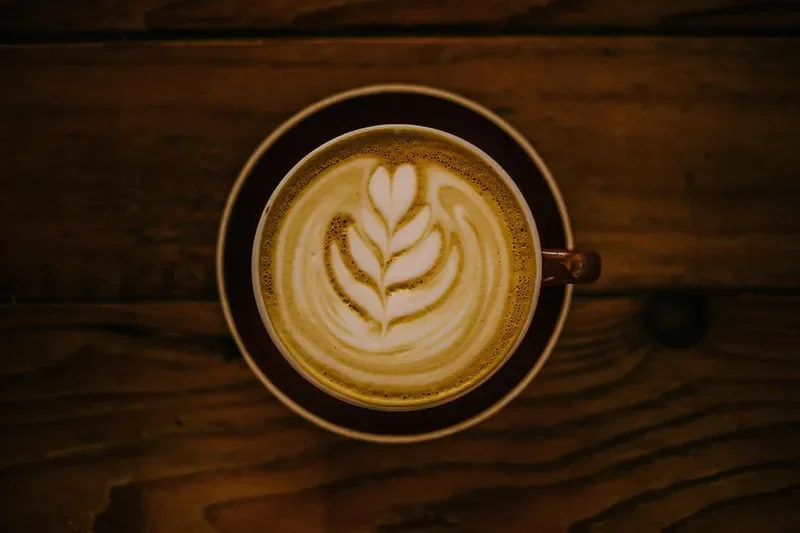 Latte in a cup on a dark brown wood table Latte in a cup on a dark brown wood table