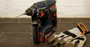 Cordless 18V rotary hammer with battery pack and work gloves on a tile floor