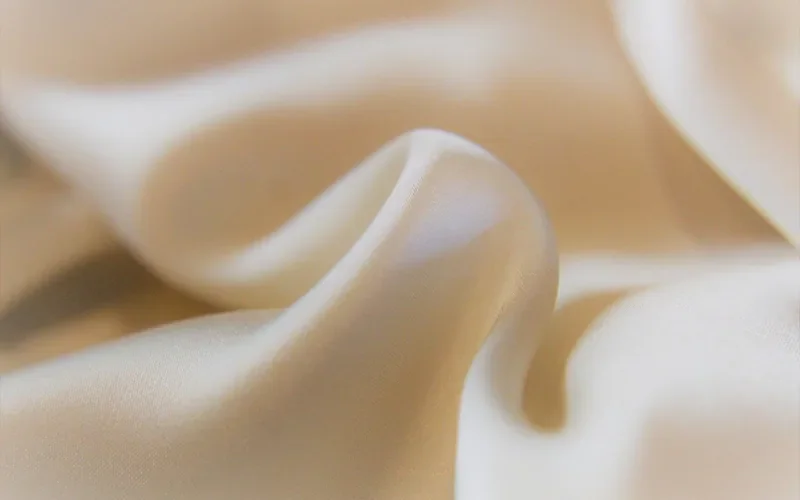 Soft folds of cream satin fabric Soft folds of cream satin fabric