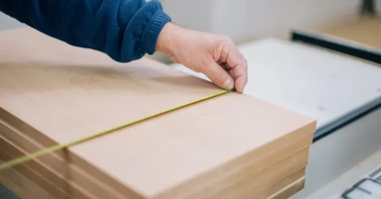 Stack of plywood panels being measured with a tape before joinery cuts