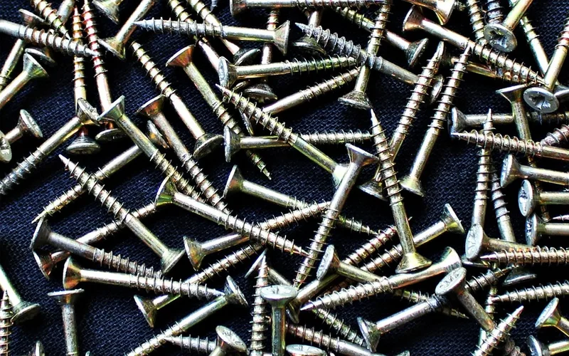 Pile of brass-coated flat head wood screws on a dark cloth