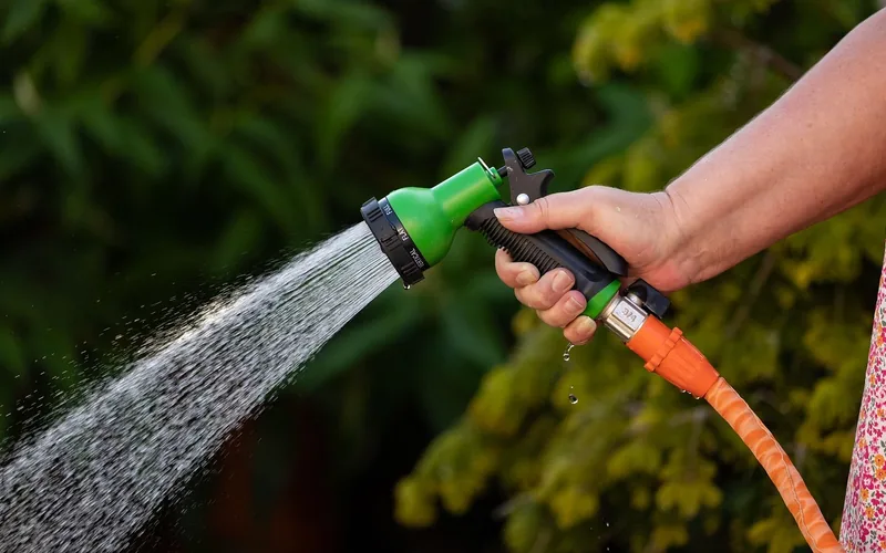 hand holding a garden hose spraying water, used to fully extinguish an outdoor fire hand holding a garden hose spraying water, used to fully extinguish an outdoor fire