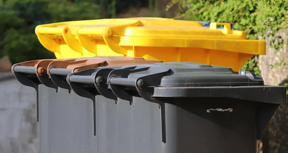 Row of household trash and recycling bins with closed lids