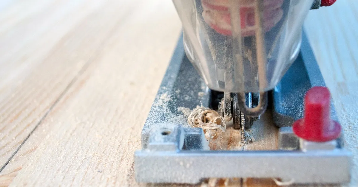 Jigsaw blade cutting into a laminate-topped board with fine sawdust