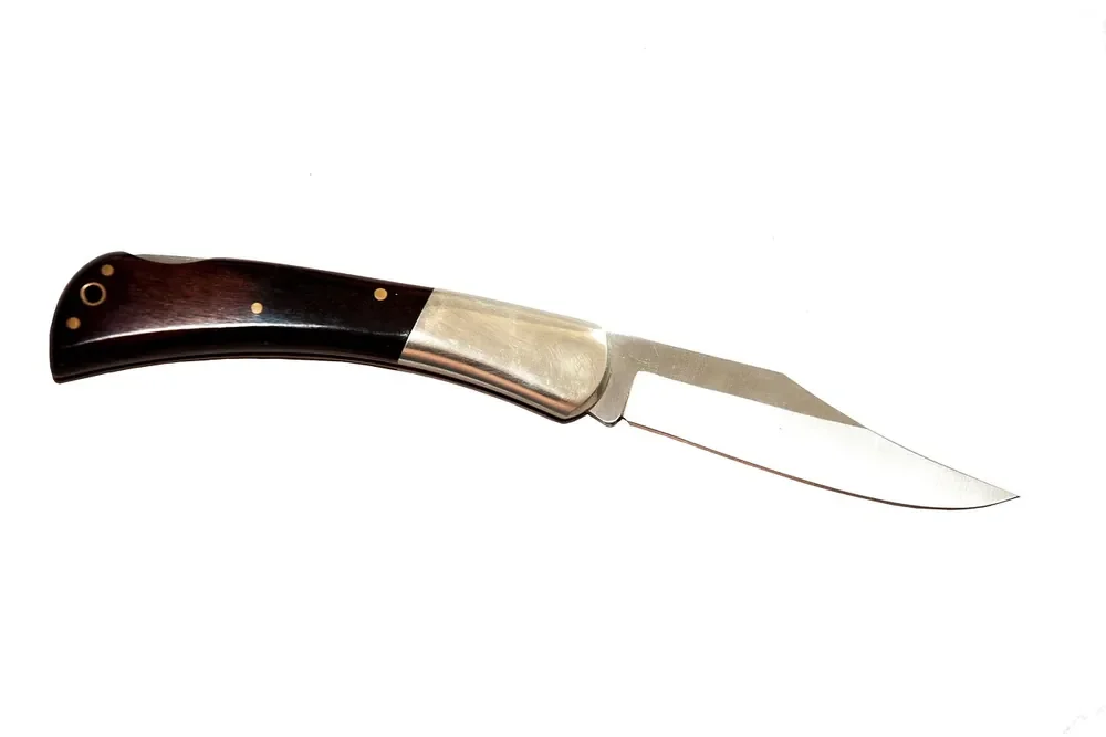 Lockback folding knife with dark wood handle scales and brass pins, blade open