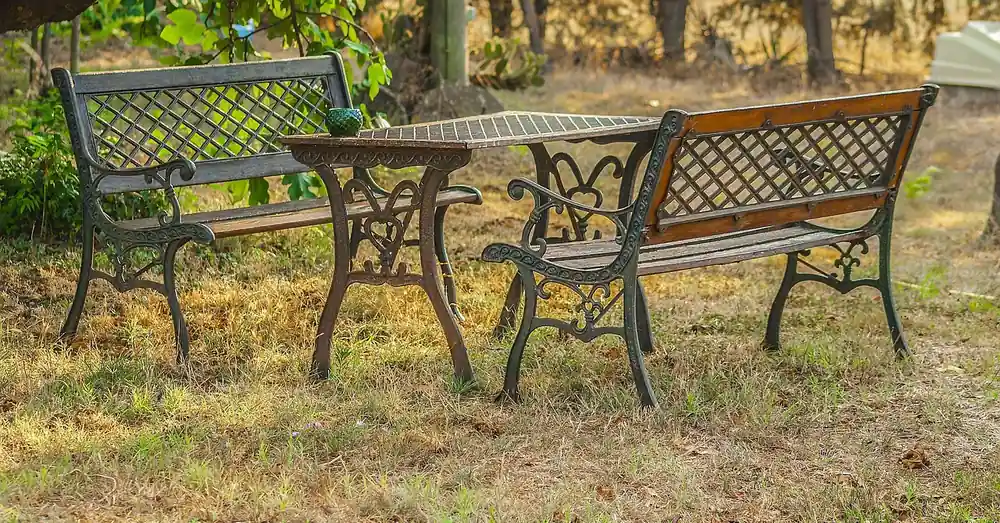 Wood-slat garden table and benches on cast iron legs