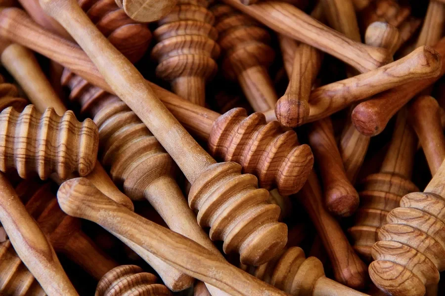 Pile of oiled olive wood honey dippers showing a soft satin finish