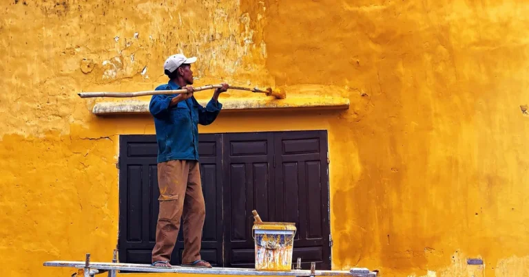 Painter on scaffolding applying coating to an exterior wall