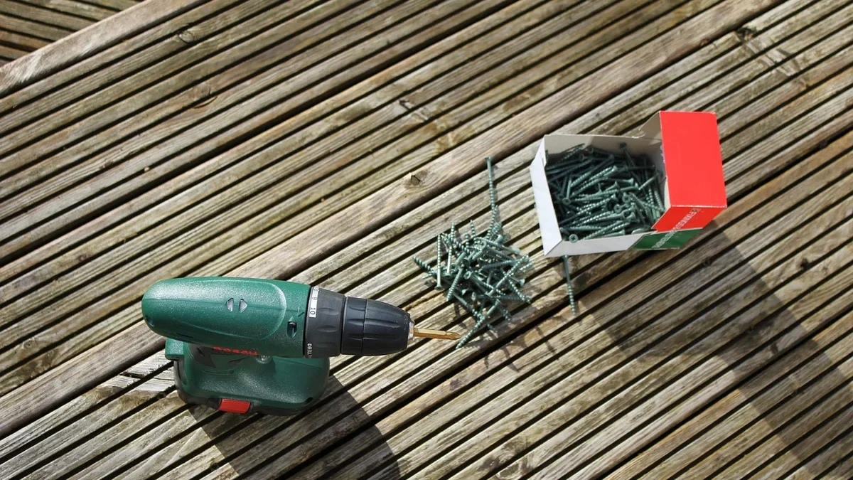 Cordless drill and box of deck screws on wooden decking