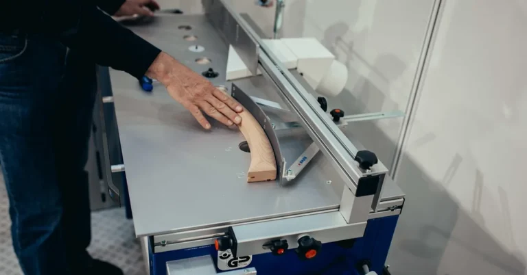 Woodworker guiding a workpiece over a stationary router table fence and insert plate