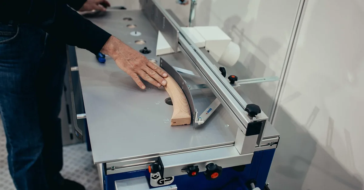 Woodworker guiding a workpiece over a stationary router table fence and insert plate