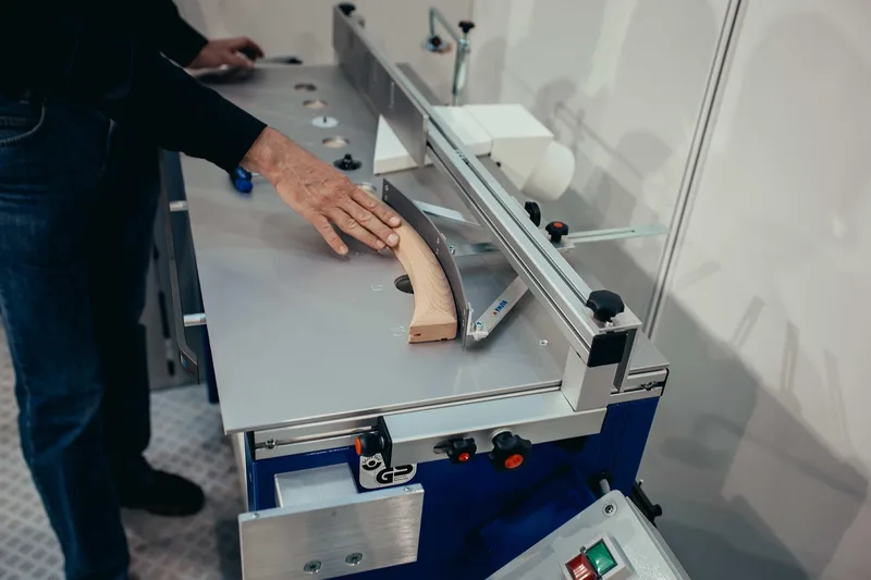 A woodworker guiding a curved workpiece along a fence on a router table to cut a round-over profile