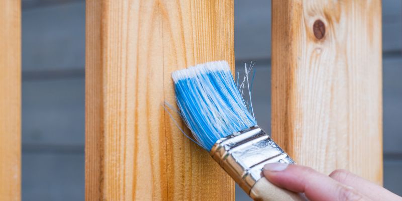 Applying wood conditioner to a wood board with a brush before staining