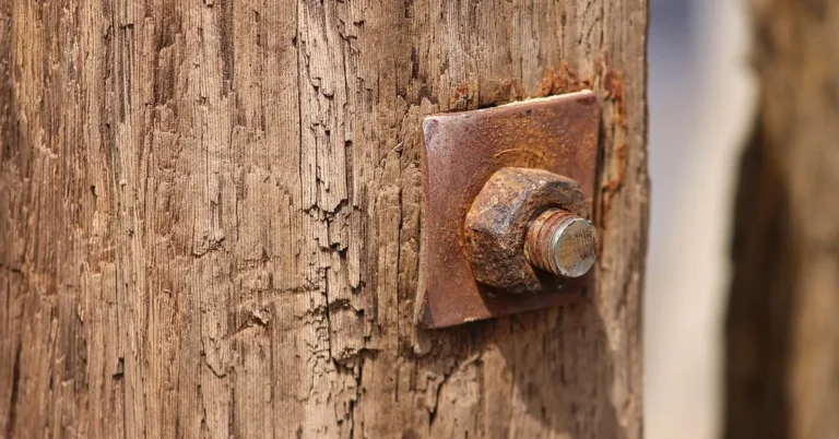 Rusty bolt and washer plate on a weathered wood post