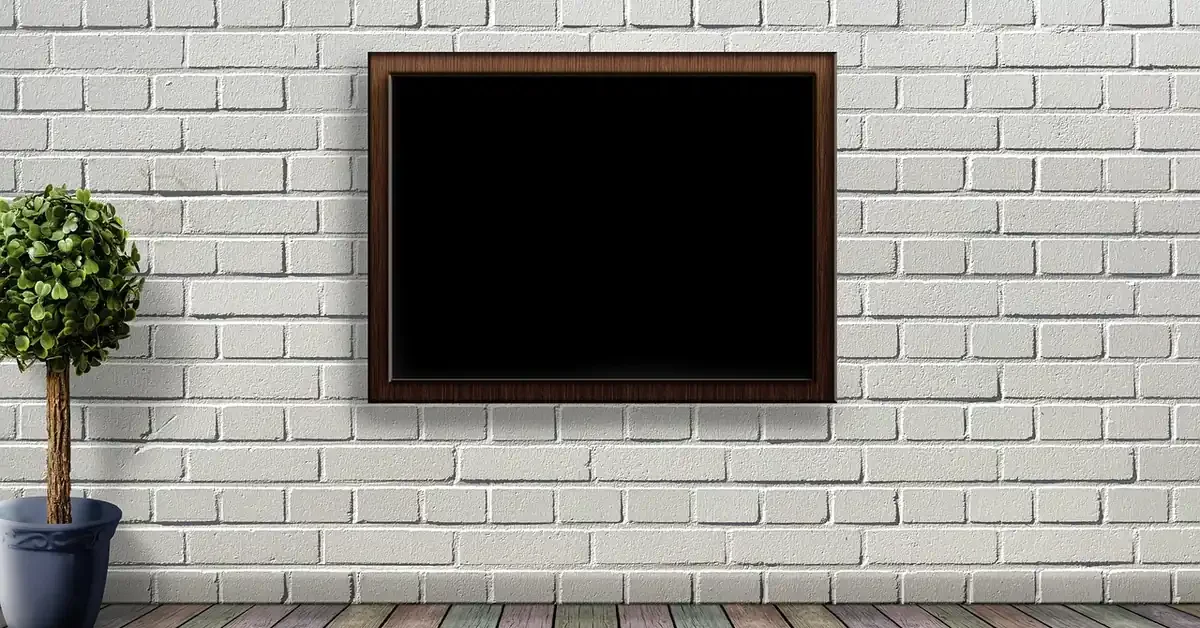 Framed picture hanging on a white brick wall from a sawtooth hanger