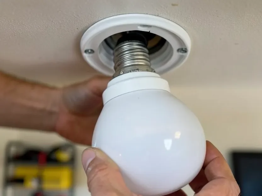 Hand screwing an E26 base LED light fixture into an open garage ceiling socket Hand screwing an E26 base LED light fixture into an open garage ceiling socket