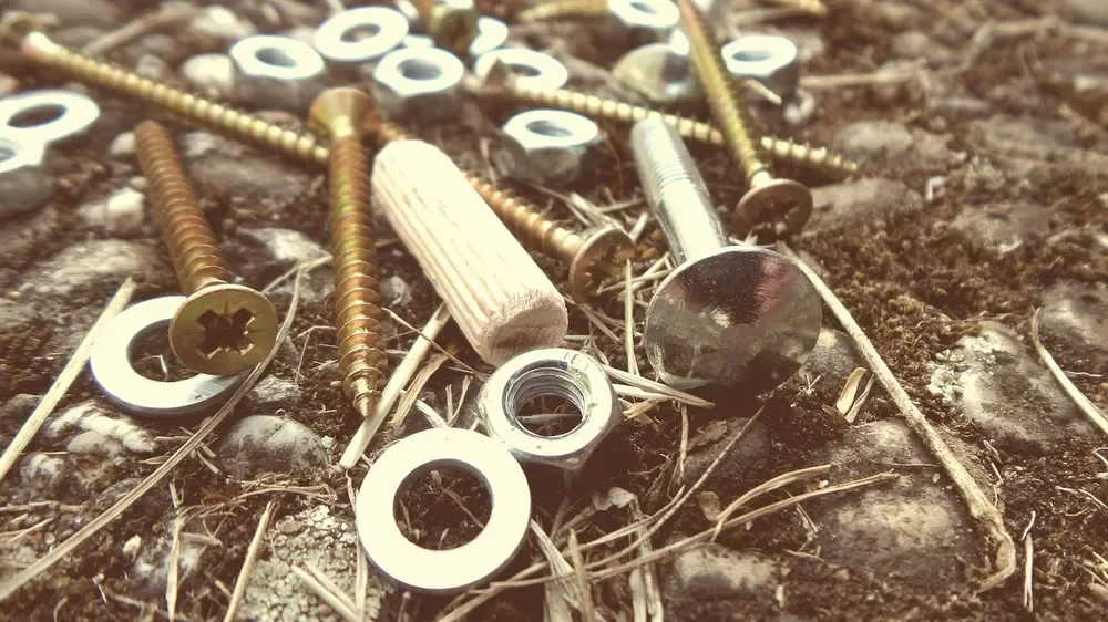 Wood screws, flat washers, a hex nut and a wooden dowel lying together