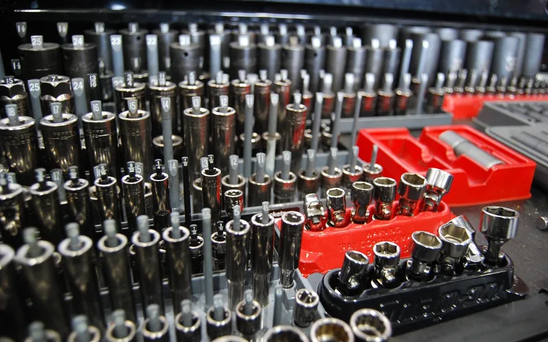 Socket and wrench set laid out for removing a lawn mower blade bolt