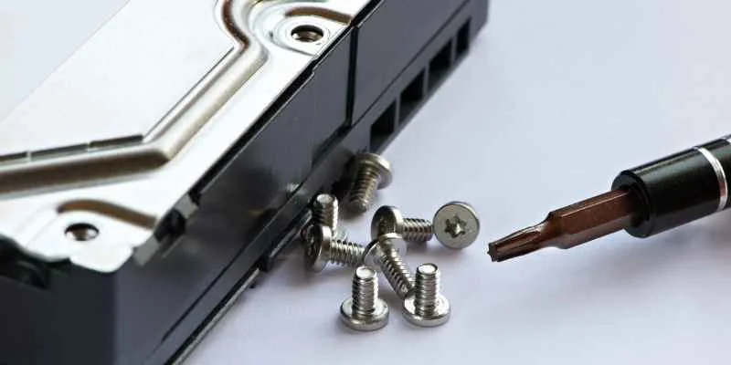 Tiny electronics screws next to a precision driver bit