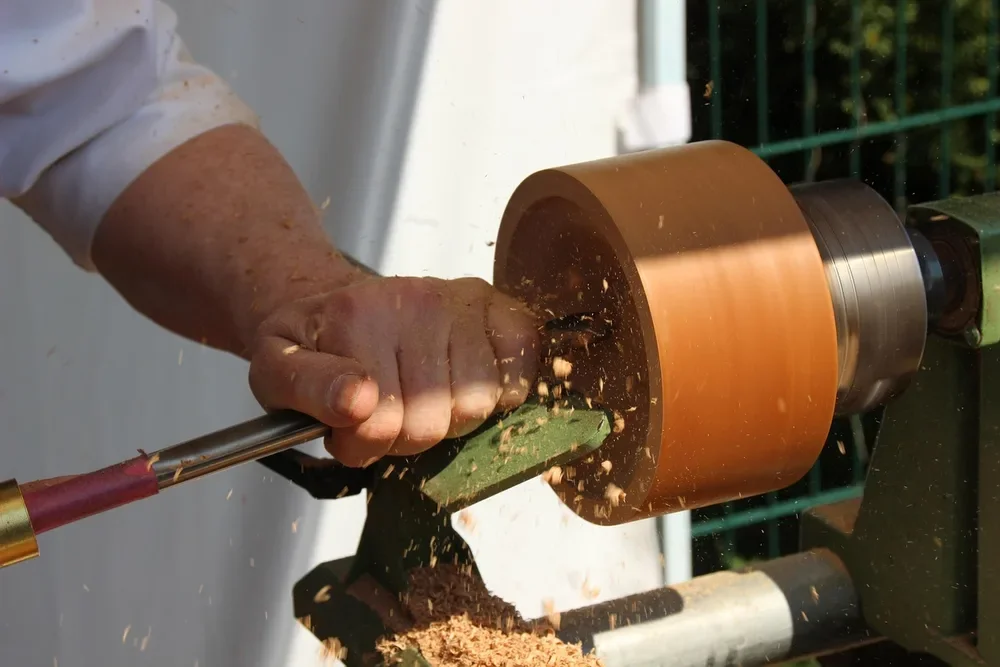Woodturner shaping a spinning wood blank on a lathe with a gouge