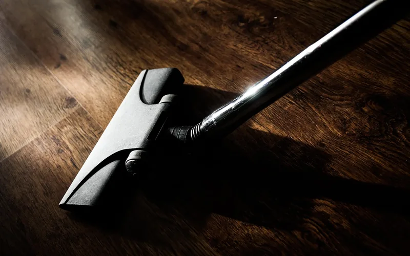 vacuum cleaner floor attachment gliding over an untreated hardwood floor