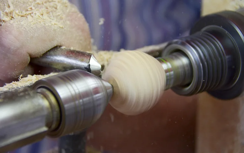 antique wood lathe used for turning logs, illustrating the spinning-blade principle behind rotary-cut veneer