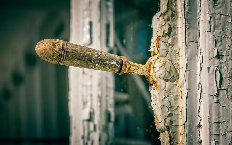 close-up of weathered wood window hardware with cracked, peeling exterior paint close-up of weathered wood window hardware with cracked, peeling exterior paint