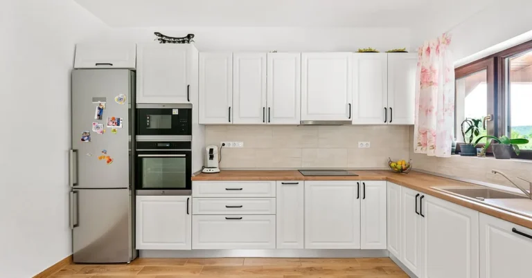 White kitchen with a run of wall cabinets above wood countertop and base cabinets
