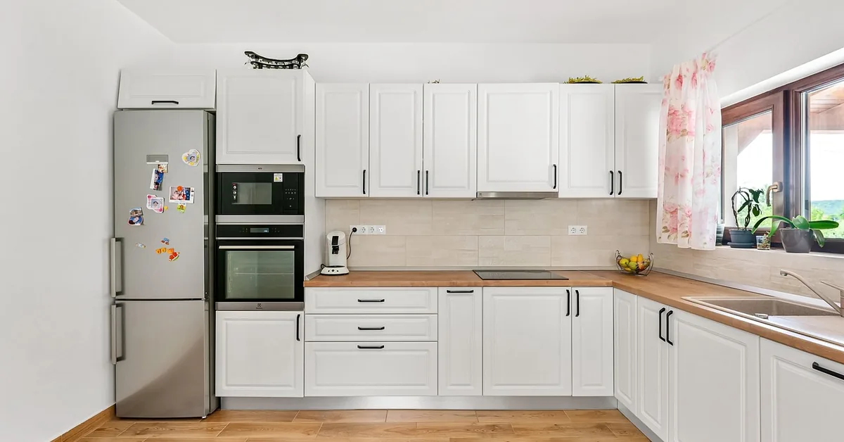 White kitchen with a run of wall cabinets above wood countertop and base cabinets
