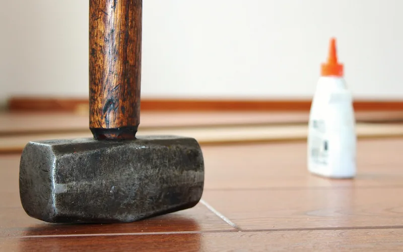 Wood glue bottle and mallet beside laminate flooring boards during installation Wood glue bottle and mallet beside laminate flooring boards during installation