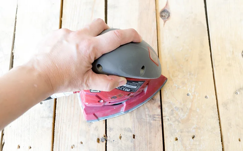 wood repair and sanding in a workshop using tools on a wood pallet surface