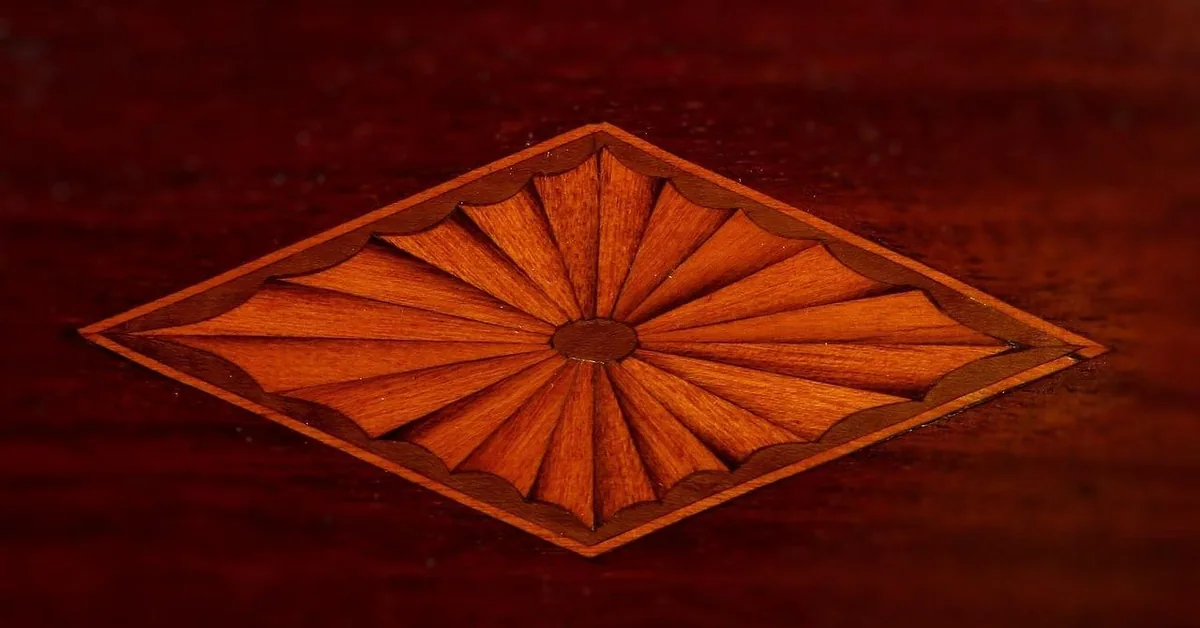 Sunburst veneer marquetry inlay on a mahogany surface