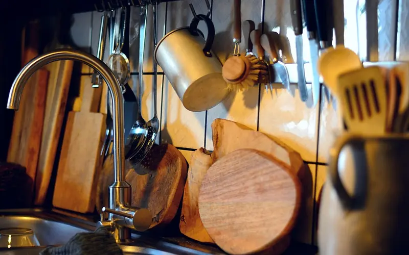 Wooden cutting boards and utensils stored beside a kitchen sink Wooden cutting boards and utensils stored beside a kitchen sink