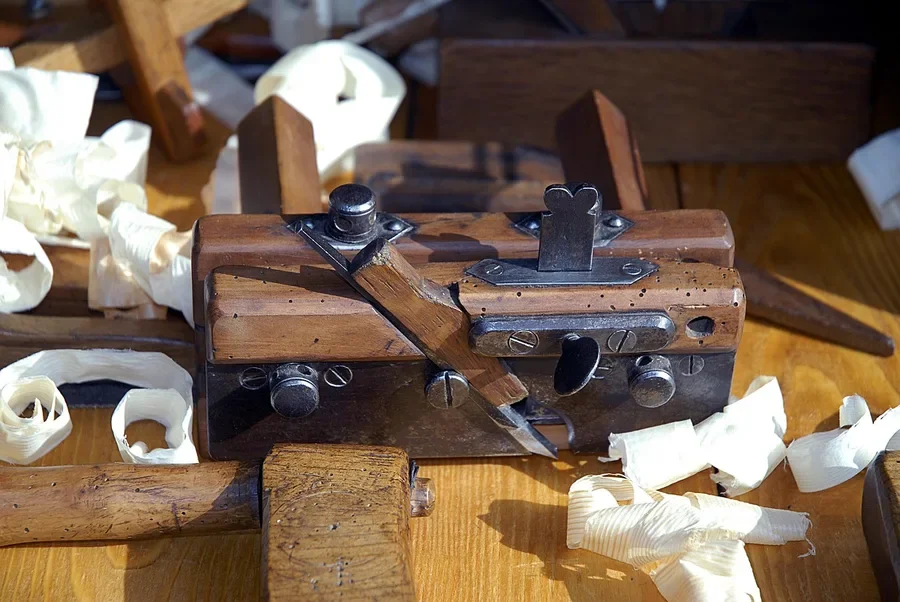 Vintage wooden-bodied plane on a workbench surrounded by curled wood shavings