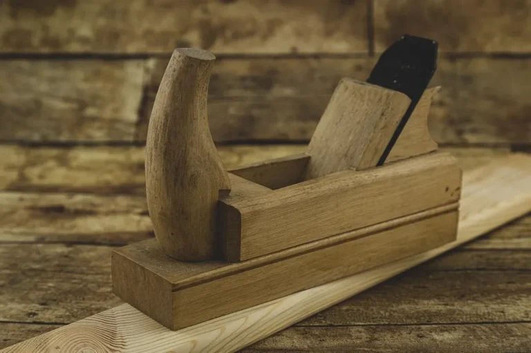 Traditional wooden hand plane with wedge and iron resting on a pine board