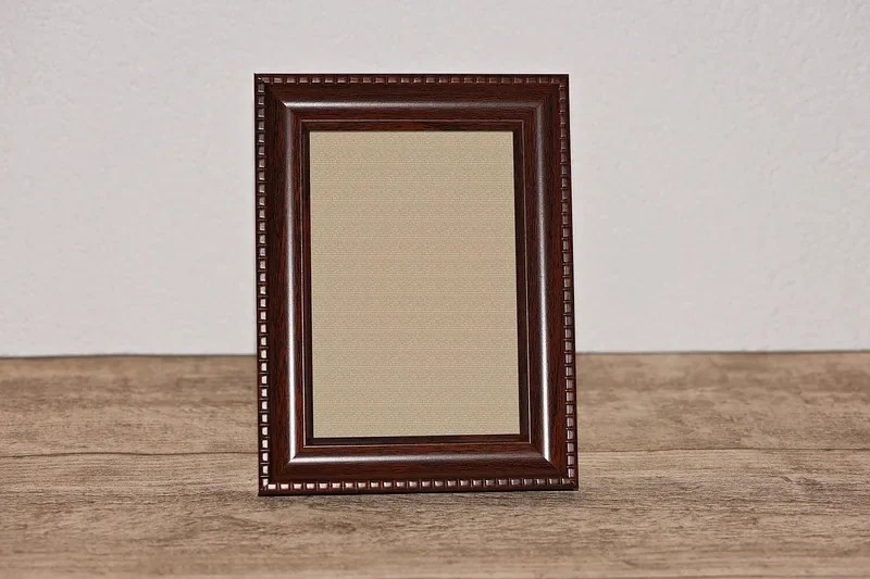 empty wooden picture frame standing on a wood surface
