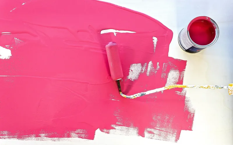roller applying pink paint to a wooden board roller applying pink paint to a wooden board